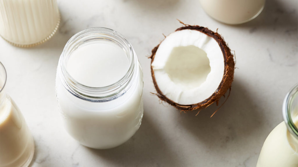 jumatate de nuca de cocos si recipient cu lapte de cocos