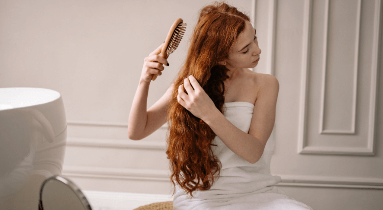 femeie roscata care isi piaptana parul