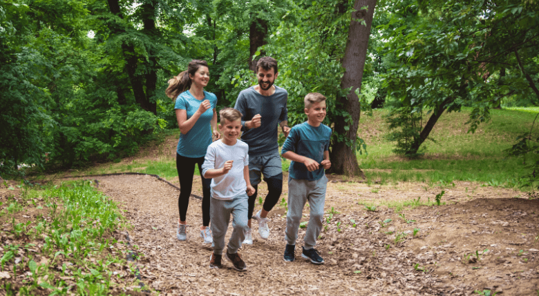 familie cu 2 baieti alergand prin parc