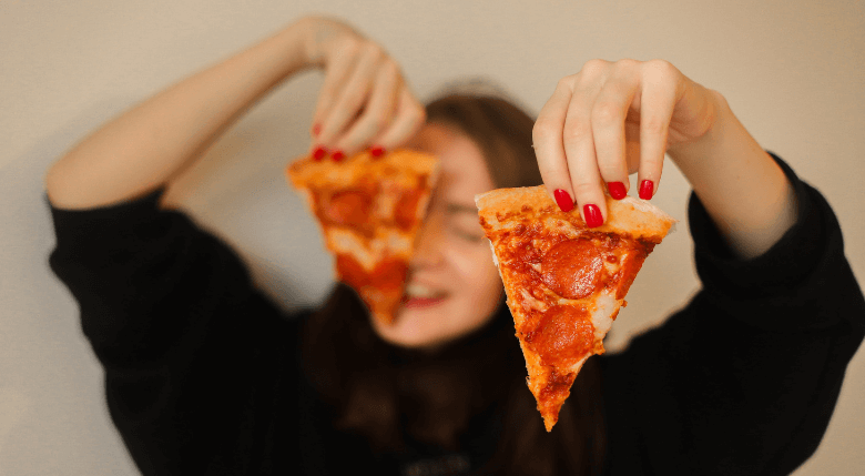 fata care tine in maini 2 felii de pizza cu salam